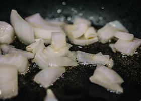 Onions, twenty minutes in, doing what only time can do.